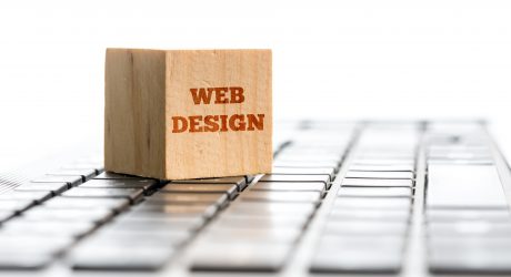 Web design, computing and e-business concept with a wooden block standing on top of a white computer keyboard with the words Web Design isolated on white with copyspace, receding perspective.